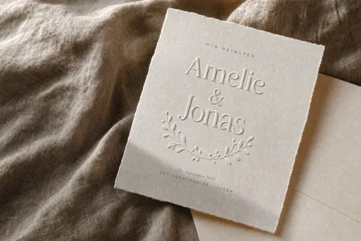 Visualisation: a botanical wreath and the names Amelie and Jonas embossed into deckle-edge handmade paper.